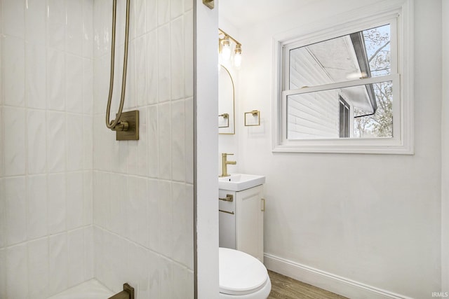 bathroom featuring a tile shower, vanity, hardwood / wood-style flooring, and toilet