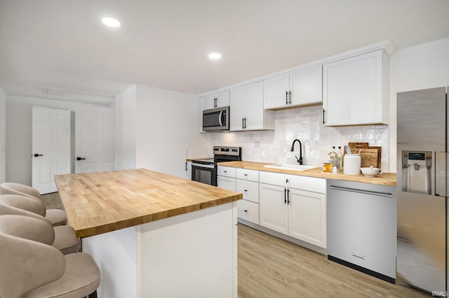 kitchen with white cabinetry, wooden counters, and appliances with stainless steel finishes