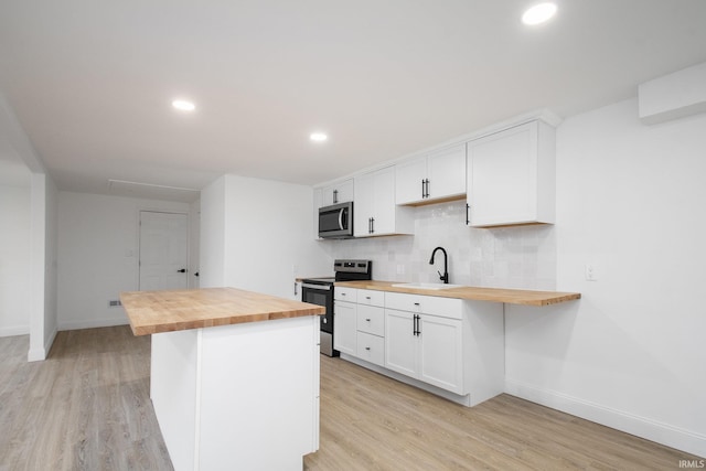 kitchen featuring wood counters, appliances with stainless steel finishes, and white cabinetry