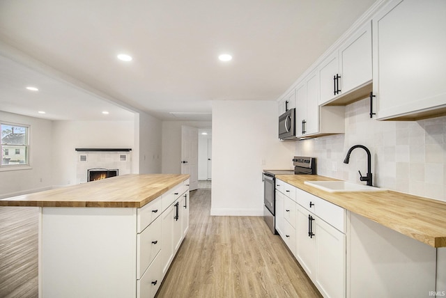 kitchen featuring white cabinetry, stainless steel electric range oven, sink, wood counters, and light hardwood / wood-style flooring