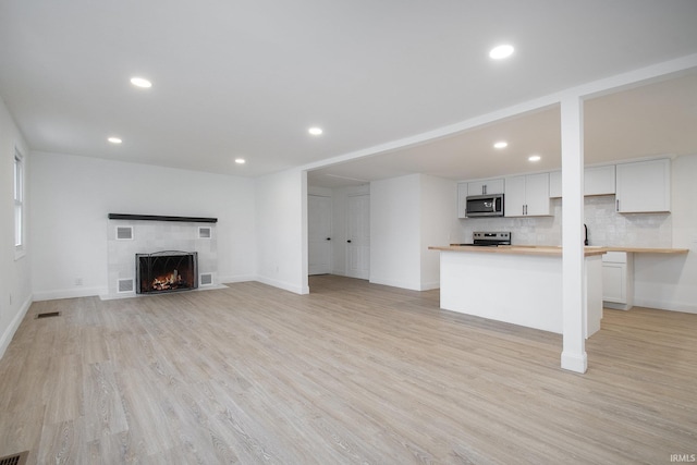 unfurnished living room with a fireplace and light hardwood / wood-style floors