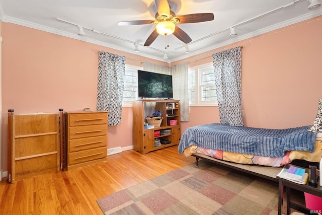 bedroom featuring hardwood / wood-style floors, track lighting, ceiling fan, and ornamental molding