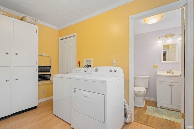 washroom featuring light wood-type flooring, washer and clothes dryer, crown molding, and sink