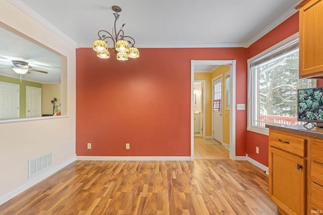 unfurnished dining area featuring ceiling fan with notable chandelier, light hardwood / wood-style floors, and crown molding