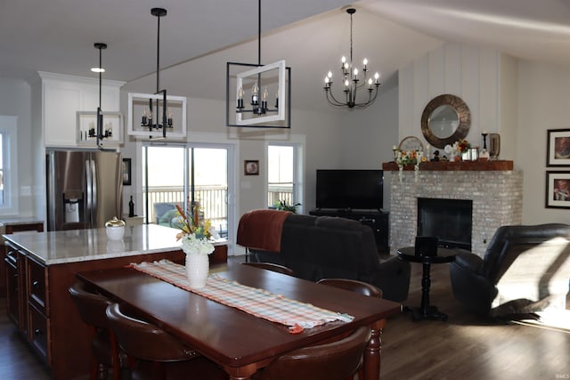 dining room with a fireplace, a chandelier, vaulted ceiling, and dark wood-type flooring