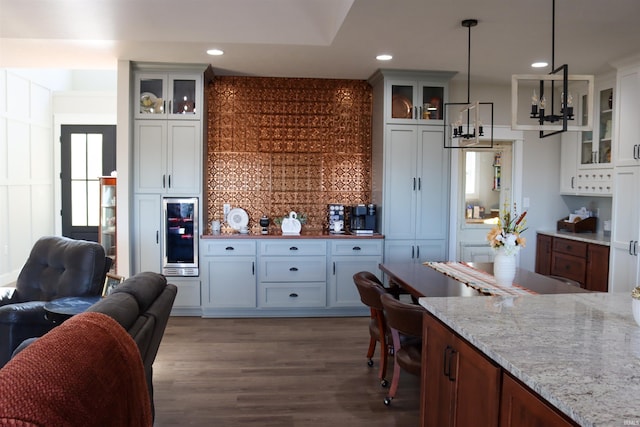 kitchen featuring white cabinetry, wine cooler, light stone counters, dark hardwood / wood-style floors, and decorative light fixtures