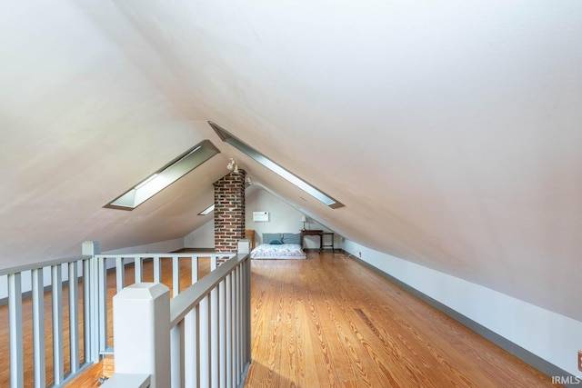 bonus room with vaulted ceiling with skylight and hardwood / wood-style floors