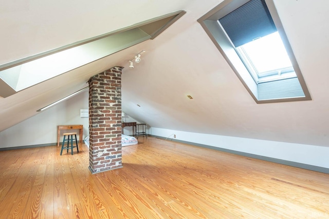 bonus room with hardwood / wood-style flooring and lofted ceiling with skylight