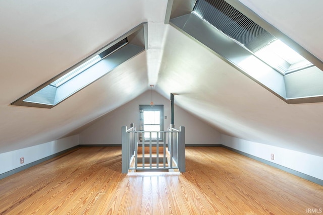 bonus room with vaulted ceiling with skylight and light hardwood / wood-style floors