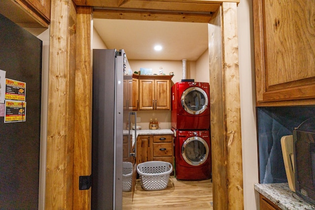 washroom featuring cabinets, stacked washer and dryer, and light hardwood / wood-style flooring