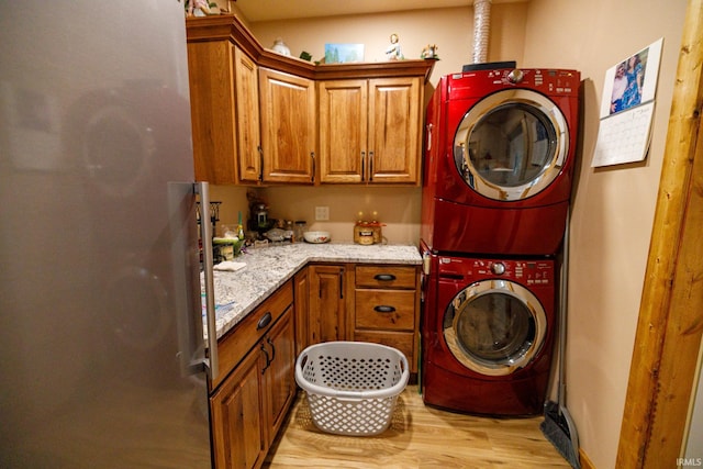 laundry area with light hardwood / wood-style flooring, cabinets, and stacked washer / drying machine