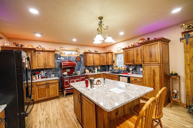 kitchen featuring decorative backsplash, dishwasher, black fridge, and a kitchen island