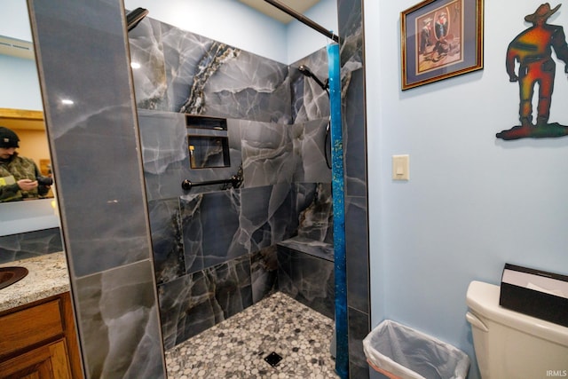 bathroom with a tile shower, vanity, and toilet