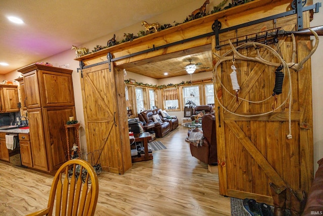 interior space with a barn door, ceiling fan, light hardwood / wood-style flooring, and sink