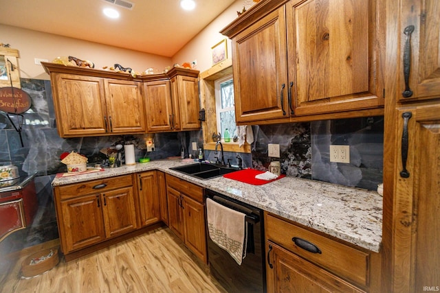 kitchen featuring tasteful backsplash, light stone counters, sink, and black dishwasher