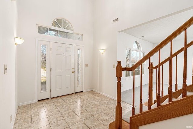 entryway with a towering ceiling and light tile patterned floors