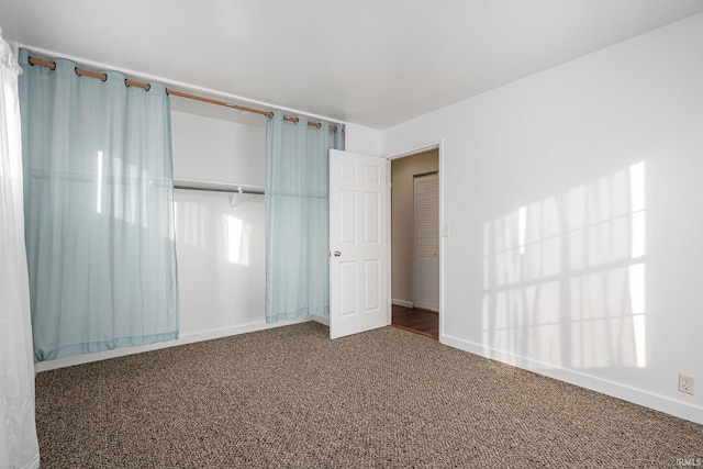 unfurnished bedroom with dark colored carpet and a closet