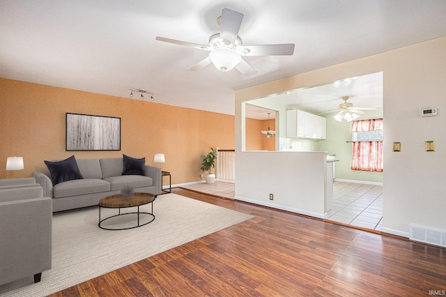 living room with hardwood / wood-style floors, rail lighting, and ceiling fan