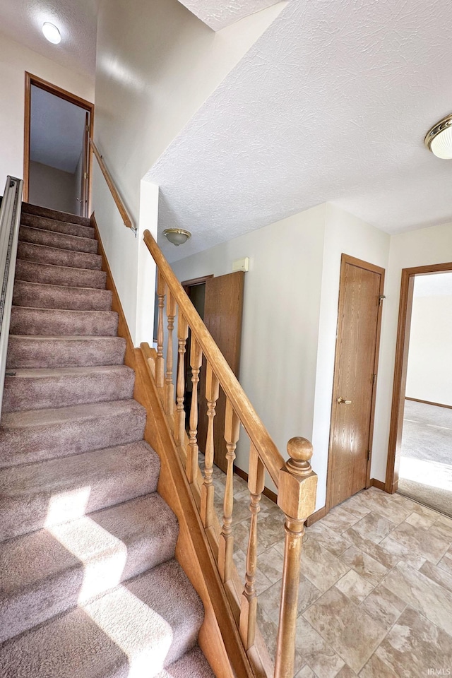 stairs featuring a textured ceiling