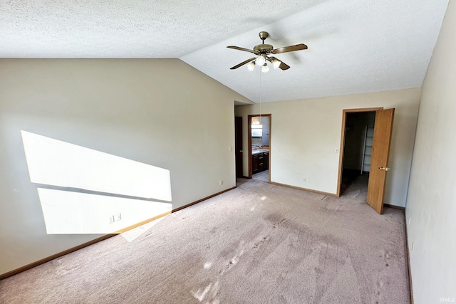 empty room featuring ceiling fan, light colored carpet, a textured ceiling, and vaulted ceiling