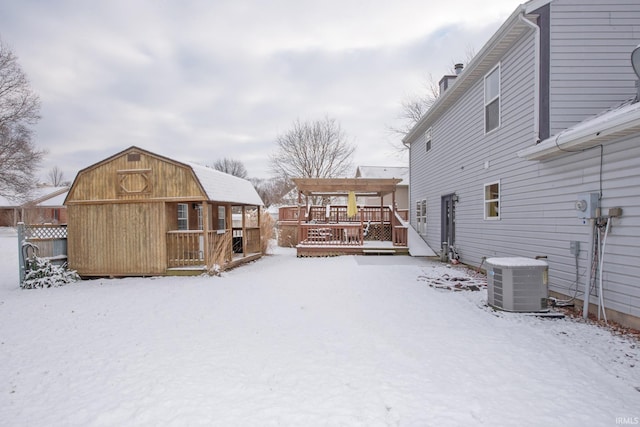 snowy yard featuring an outbuilding, cooling unit, and a deck