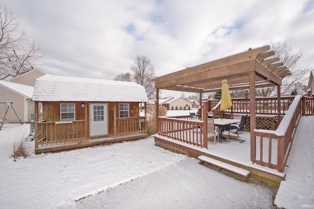 snow covered deck with a pergola and an outdoor structure