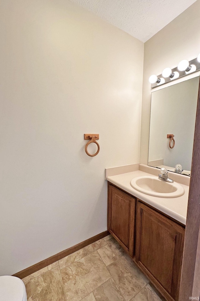 bathroom with vanity, toilet, and a textured ceiling