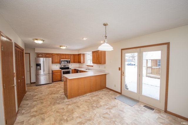 kitchen with sink, stainless steel appliances, kitchen peninsula, plenty of natural light, and pendant lighting