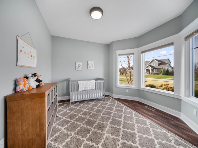 bedroom featuring a crib and dark hardwood / wood-style flooring