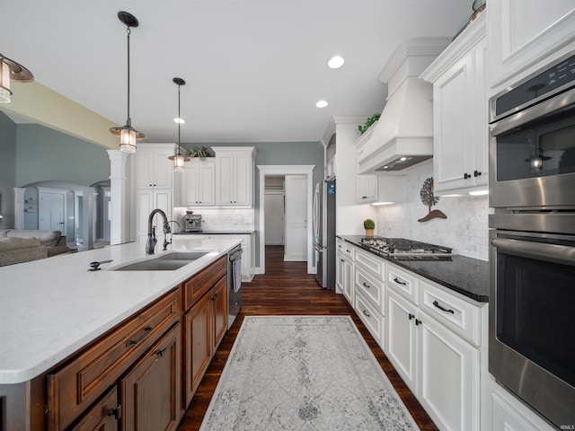 kitchen featuring white cabinets, stainless steel appliances, a center island with sink, and sink