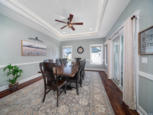 dining space featuring a raised ceiling, ceiling fan, and dark hardwood / wood-style flooring