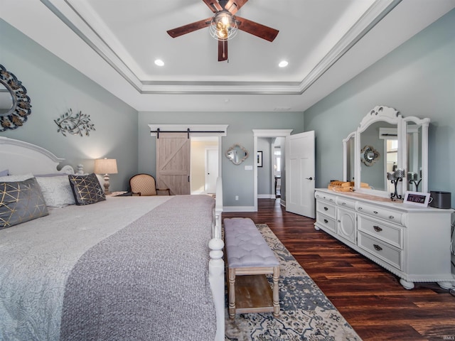 bedroom with ceiling fan, a barn door, a raised ceiling, and dark hardwood / wood-style floors