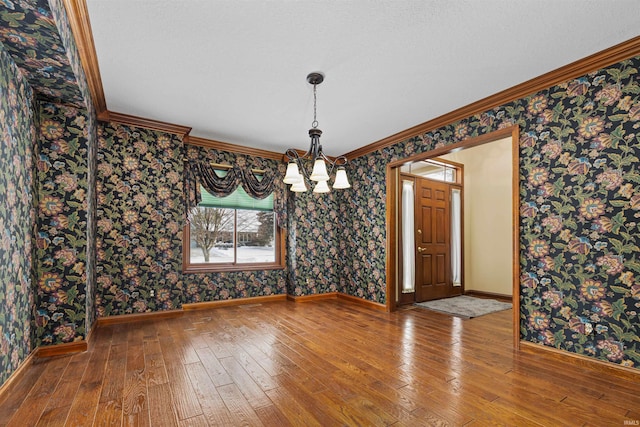 unfurnished dining area featuring wood-type flooring, ornamental molding, and a chandelier