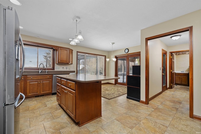 kitchen featuring sink, appliances with stainless steel finishes, hanging light fixtures, plenty of natural light, and a kitchen island