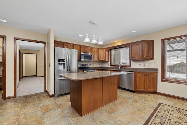 kitchen featuring tasteful backsplash, appliances with stainless steel finishes, hanging light fixtures, and a kitchen island