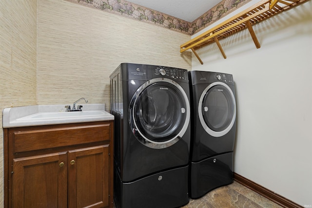 clothes washing area featuring washer and dryer, sink, and cabinets