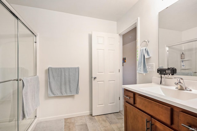 bathroom with hardwood / wood-style floors, vanity, and a shower with shower door