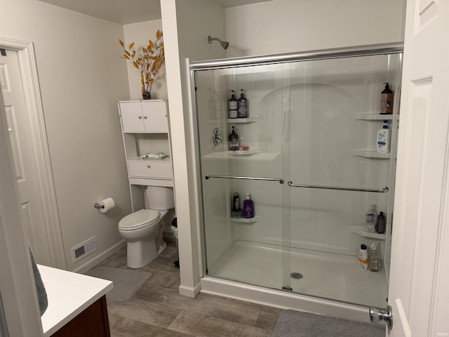 bathroom with toilet, hardwood / wood-style floors, vanity, and walk in shower