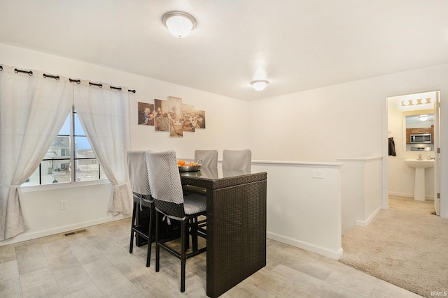 dining room featuring sink and light carpet