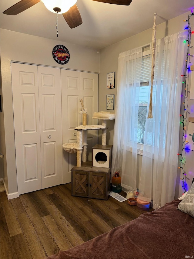 bedroom featuring dark hardwood / wood-style flooring, ceiling fan, and a closet