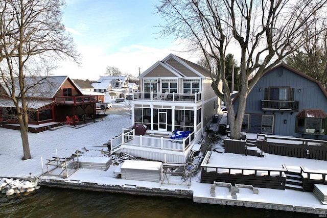 snow covered property with a deck with water view and a balcony