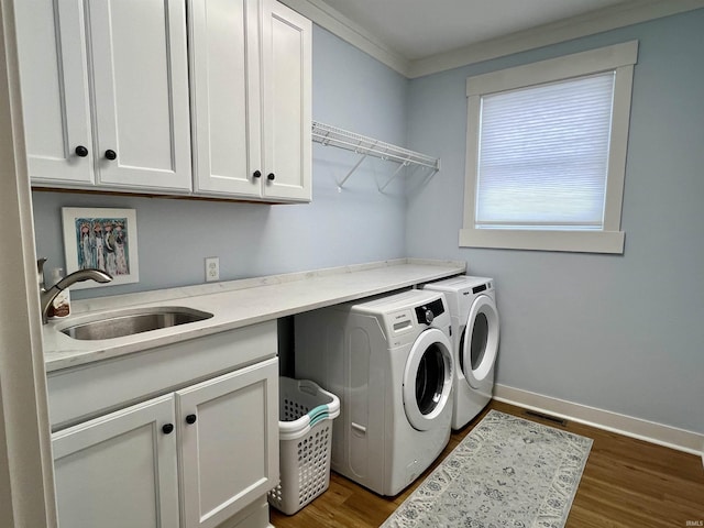 washroom with cabinets, dark wood-type flooring, crown molding, washer and dryer, and sink