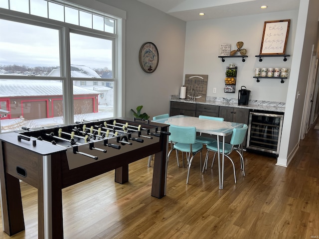 recreation room with wood-type flooring, beverage cooler, and bar area