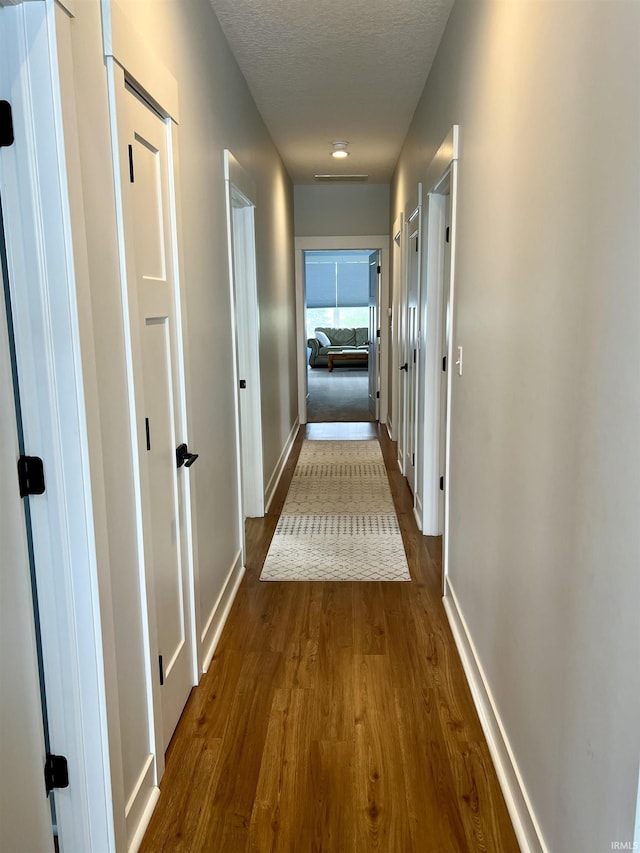 hall with hardwood / wood-style flooring and a textured ceiling