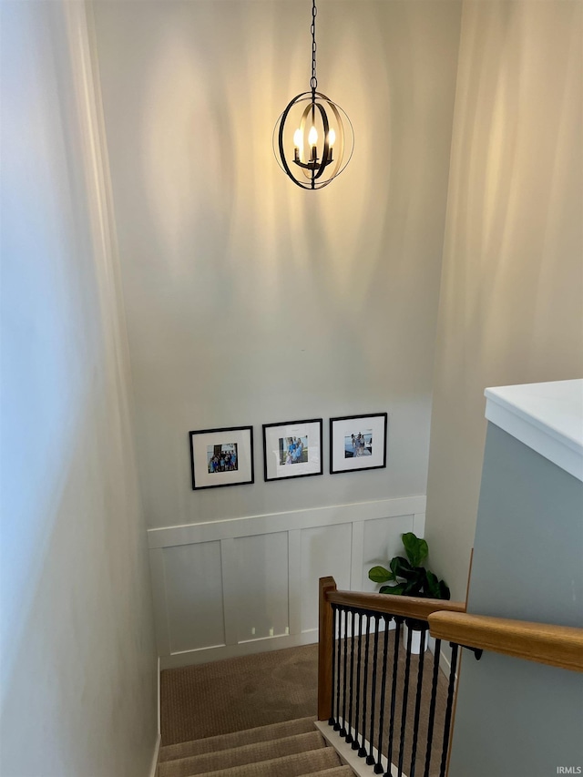 stairs with carpet flooring and a chandelier