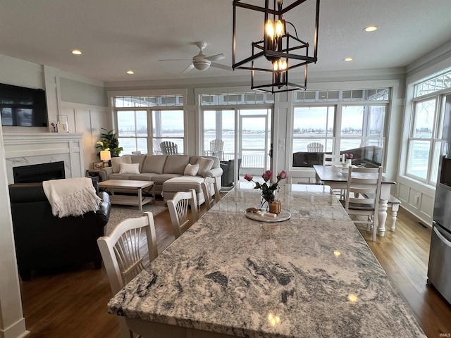 kitchen featuring light stone countertops, a premium fireplace, pendant lighting, a water view, and white cabinets