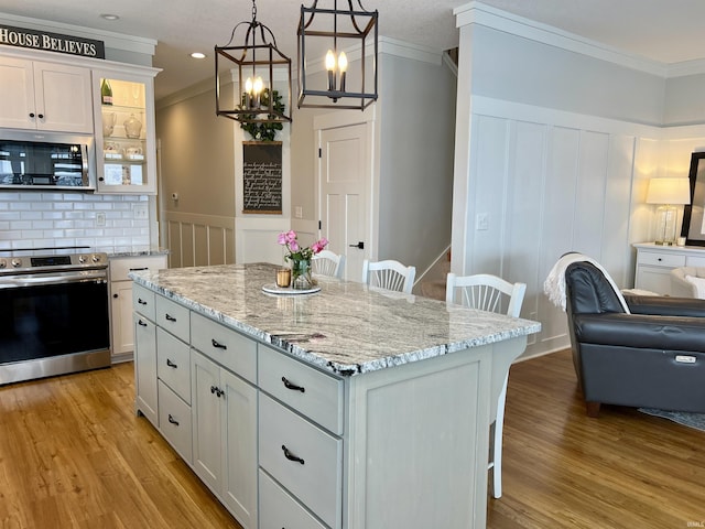 kitchen featuring white cabinetry, range, a kitchen bar, a kitchen island, and ornamental molding