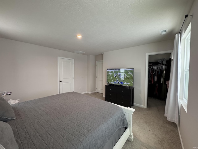 bedroom with carpet, a textured ceiling, a walk in closet, and a closet