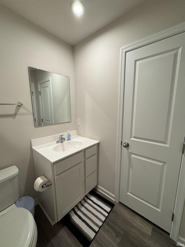 bathroom with vanity, toilet, wood-type flooring, and a textured ceiling