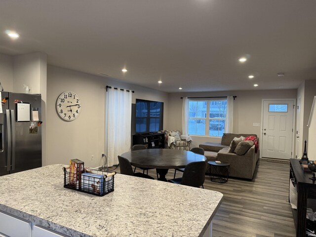 kitchen with a kitchen island with sink, white cabinets, dark hardwood / wood-style floors, and stainless steel refrigerator with ice dispenser